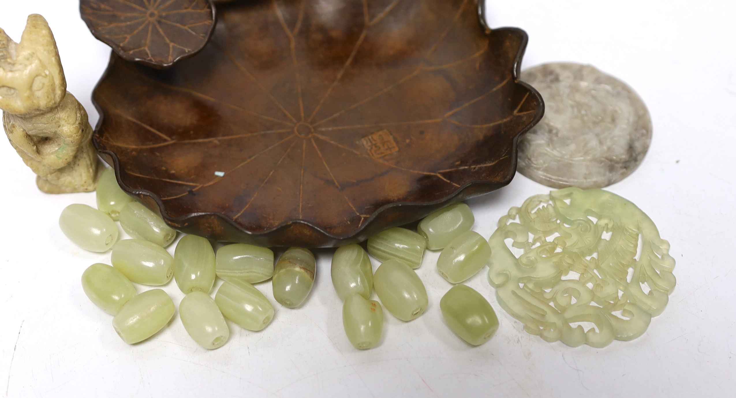 A collection of Chinese items including a bronze tray in the form of a water lily, two bowenite or jadeite discs, a soapstone cat and a bag of hardstone beads, bronze 14cm diameter